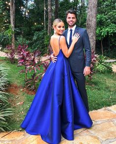 a man and woman standing next to each other in front of some trees with lights