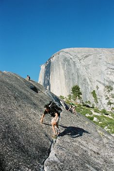 a man climbing up the side of a mountain with a backpack on his back and two other people in the background