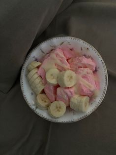 a white plate topped with sliced bananas and pink jellie on top of a bed