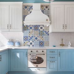 a kitchen with blue and white tiles on the backsplash, stove top oven and range hood