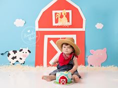 a little boy sitting on the floor in front of a barn and farm animals backdrop