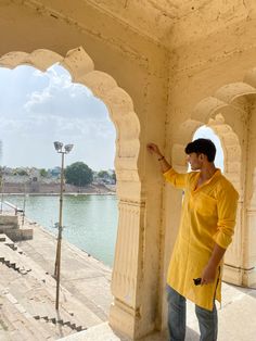 a man standing next to a wall near water