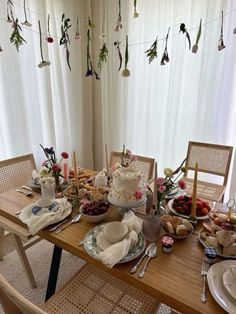 a wooden table topped with lots of plates and bowls filled with food next to a window