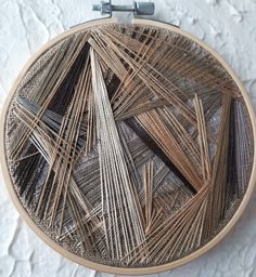 a close up of a circular wooden frame with thread on the bottom and metal pins attached to it