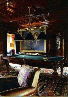 a pool table in the middle of a living room with couches and paintings on the wall