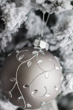 a silver ornament hanging from the side of a tree with snow on it