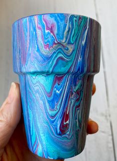 a hand holding a blue and purple marbled cup