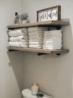 towels are stacked on shelves above a toilet