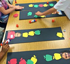 children are playing with construction paper on the table