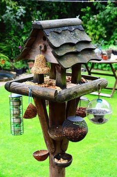 a wooden bird feeder filled with lots of birds and seed hanging from it's sides