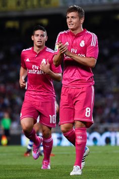 two soccer players in pink uniforms are running on the field with their arms around each other