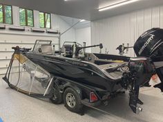 a boat is parked in a garage next to a trailer with a motor on it