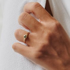 a woman's hand wearing a gold ring with a green stone on it and a white towel