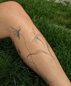 a woman's legs with tattoos on them laying in the grass