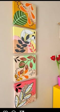 three paintings are hanging on the wall next to a vase with red flowers in it