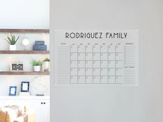 a family calendar hanging on the wall next to a shelf with boxes and other items