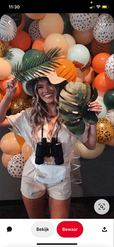 a woman standing in front of a wall with balloons and hats on it's head