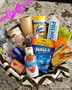 a basket filled with snacks and drinks on top of a marble countertop next to a pink bow