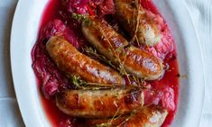 sausages with red sauce and herbs on a white plate