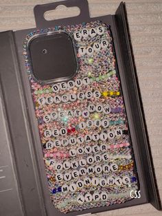 an open cell phone case with words and beads on it sitting on a table next to a keyboard