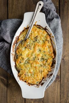 a casserole with cheese and spinach in a white dish on a wooden table