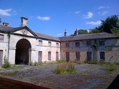 an old building with lots of windows and no doors on the outside, surrounded by overgrown vegetation