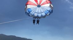 two people are attached to a parachute in the sky