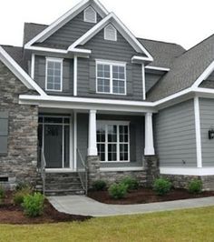 a house with gray siding and white trim on the windows, two car garages