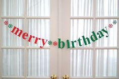 a merry birthday banner hanging from the side of a white door in front of two windows