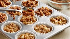 a muffin tin filled with cupcakes on top of a counter next to a bowl of nuts