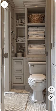 a white toilet sitting inside of a bathroom next to a closet filled with lots of towels