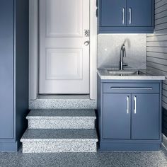 a kitchen with blue cabinets and stairs leading up to the door