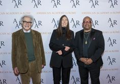 three people standing next to each other on a red carpet