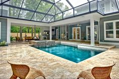 an indoor swimming pool surrounded by wicker chairs