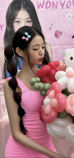 a girl in a pink dress holding balloons and a hello kitty sign behind her back