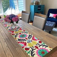 a dining room table with flowers on it and blue chairs in the backround