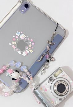 a cell phone and camera sitting next to each other on a white surface with an animal charm