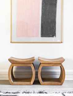 two wooden stools sitting in front of a painting