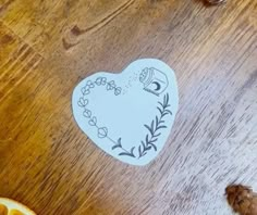 a heart shaped sticker sitting on top of a wooden table next to sliced oranges