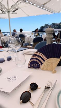 the table is set with glasses, silverware and an umbrella