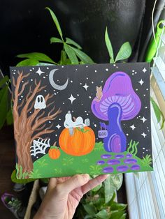 a hand holding up a card with halloween scenes on it and pumpkins in the background