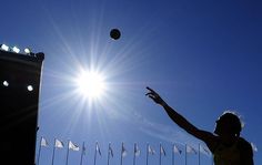 a person throwing a frisbee in the air near many flags and poles on a sunny day