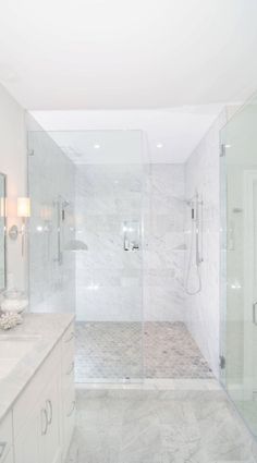 a white bathroom with two sinks and a walk in shower