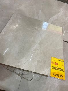 a piece of white marble sitting on top of a floor next to a yellow tag