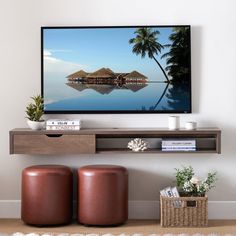 a flat screen tv sitting on top of a wooden shelf next to two stools