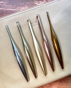 four different types of dental instruments sitting on top of a white leather bag with wood flooring