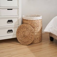 a wicker basket sitting on the floor next to a white dresser with drawers in it