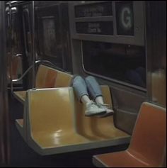 a person sitting on a subway train with their feet up against the seat and legs down