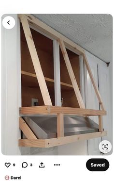 an open window in the wall with some wood frame around it and a metal shelf below