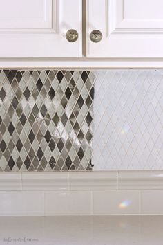 a kitchen with white cabinets and tile backsplash